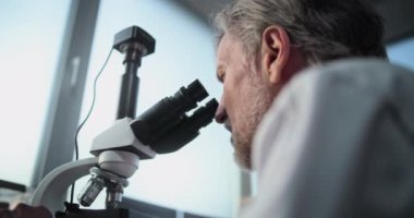 Fosil örneğini mikroskop altında inceleyerek bilimsel araştırmalar yapan olgun bilim adamlarına yakın durun. Mikrobiyolog arkeoloji laboratuvarında gelişmiş ekipmanlarla çalışıyor. Bilimsel yöntem.