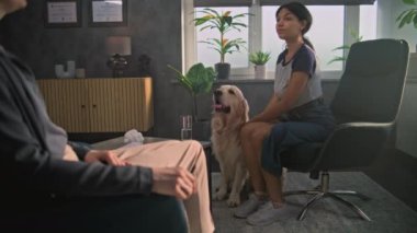 Afrika kökenli Amerikalı genç kız terapist dinliyor danışmanlık sırasında Golden Retriever köpeği besliyor. Kadın psikolog, ergen için terapi sağlıyor. Akıl sağlığı. Yavaş Hareket.
