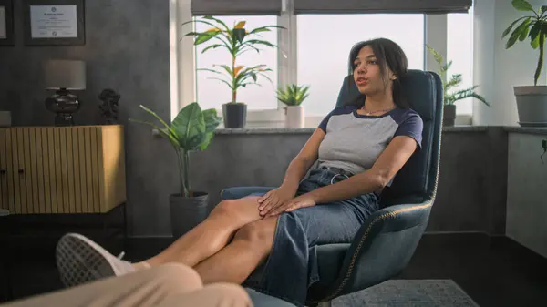 stock image Relaxed African American teen girl sits in chair, shares positive emotions with psychotherapist, finds solution during counseling therapy session. Psychotherapy and psychological help. Mental health.