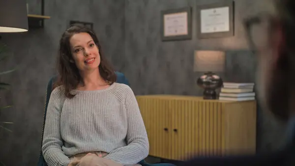 stock image Adult woman sits in chair, discusses problems with psychologist, finds solution on counseling session. Female patient during therapy with professional psychotherapist. Psychology and mental health.