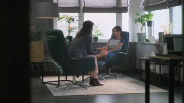 Psikoterapistle terapi seansında olan depresyondaki Afrikalı Amerikalı kız. Kadın psikoloğun arka planda oturup dinlemesi. Genç hasta sorunlardan bahsediyor, aile meselelerini tartışıyor..