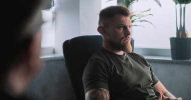 Travma sonrası stres bozukluğuyla kamufle olmuş, psikoterapist veya psikologla terapi seansında duygularını paylaşan depresif bir asker. Travma sonrası stres bozukluğu. Omzunun üstünden..