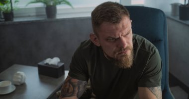 Erkek asker psikoterapist ya da psikologla konuşur, duygularını paylaşır. Psikoterapi seansı sırasında ağlayan stresli asker portresi. Travma sonrası stres bozukluğu. Ruh Sağlığı.