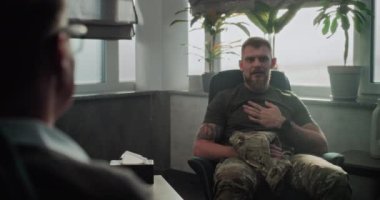 Askeri üniformalı adam sandalyede oturup gelişmeleri tartışıyor ve başarılı terapi veya rehabilitasyondan sonra psikoterapistle tokalaşıyor. Profesyonel psikolog askerleri dinler..