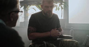 Fiziksel engelli bir asker terapide ilerlemeyi tartışıyor, rehabilitasyondan sonra psikologla tokalaşıyor. Tekerlekli sandalyedeki erkek asker kıdemli psikoterapiste veda etti ve gitti..
