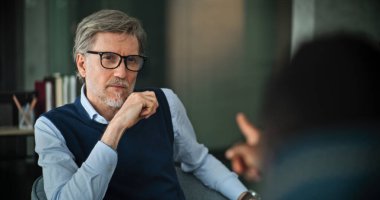 Profesyonel evlilik danışmanı kürsüye oturur, konuşur ve muayene sırasında hastaları dikkatle dinler. Olgun psikolog sorunları analiz eder, çift terapisi sağlar. Psikolojik yardım.