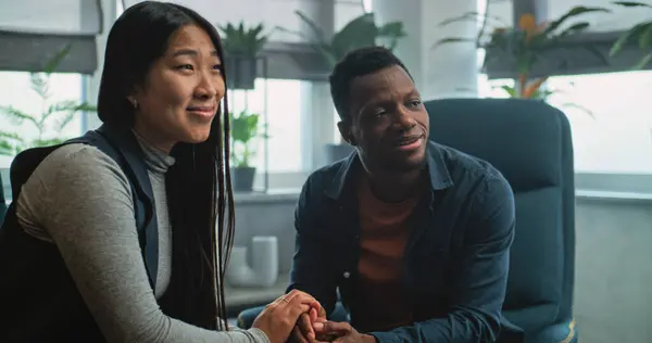 Terapistle terapi seansında çok ırklı mutlu bir çift. Afrikalı Amerikalı erkek ve Asyalı kadın çiftler terapisinde el ele tutuşarak sandalyelere otururlar. Psikolog genç bir aileyle konuşuyor..