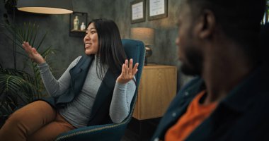 Kız arkadaşını dinleyen, çiftler terapisi sırasında su içen yorgun Afrikalı Amerikalı adama yakın durun. Arka planda Asyalı kadın terapi seansında psikologla ilişkisini tartışıyor..