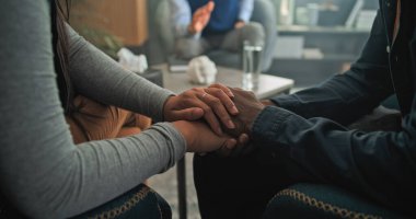 Başarılı çiftler terapisinde çözümü bulduktan sonra sandalyeye oturup el ele tutuşan çok ırklı çiftlerin yakınlaşması. Genç aileyle terapi seansına odaklan..