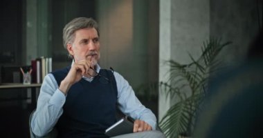 Profesyonel evlilik danışmanı koltukta oturur, hastaları dikkatle dinler. Olgun psikolog sorunu analiz eder, çift için grup terapisi sağlar. Psikoloji konsepti.