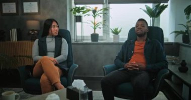 Afrikalı Amerikalı erkek ve Asyalı kadın sandalyeye oturur, evlilik ve ilişki sorunlarını tartışır, çiftler terapisi konusunda anlaşmazlığa düşerler. Terapistin danışmanlık seansında genç bir aileyi dinlemesi..
