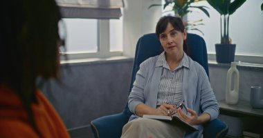 Psikoterapi ofisinde randevusu olan genç bir hasta. Kadın terapist sandalyeye oturur, müşteriyi dikkatle dinler. Afrikalı Amerikalı genç psikologla konuşuyor. Psikolojik yardım.