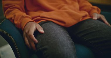 Gergin ve stresli Afrikalı Amerikalı çocuğun terapist seansı sırasında sandalyede oturup el kol hareketi yapması. Zihinsel bozuklukların tedavisi. Psikoloji ve psikoterapi kavramı.