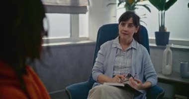 Psikoterapi ofisinde randevusu olan genç bir hasta. Kadın terapist sandalyeye oturur, müşteriyi dikkatle dinler. Afrikalı Amerikalı genç psikologla konuşuyor. Psikolojik yardım.