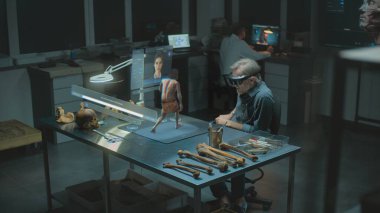 Gelişmiş arkeoloji laboratuvarı: VR kulaklık uzmanı arkeolog yapay zeka simülatöründe antik insan evrimini araştırıyor, artırılmış gerçekliği kullanarak araştırma yapıyor. Yapay zeka asistanıyla birlikte üç boyutlu sanal görüntü oluşturma. VFX