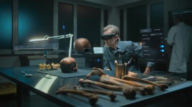 Gelişmiş arkeoloji laboratuvarı: VR kulaklık alanında arkeolog fosil kafatası kullanarak eski insan anatomisini artırılmış gerçeklikte inceliyor. Tarama yazılımının kullanıcı arayüzü ile üç boyutlu görüntüleme.