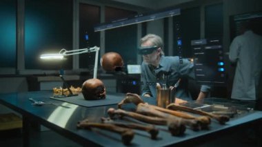 Gelişmiş arkeoloji laboratuvarı: VR kulaklık alanında arkeolog fosil kafatası kullanarak eski insan anatomisini artırılmış gerçeklikte inceliyor. Tarama yazılımı arayüzü ile sanal görüntünün 3 boyutlu canlandırması.