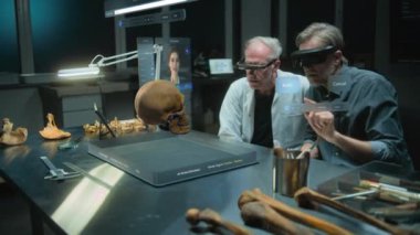 Gelişmiş arkeoloji laboratuvarı: VR kulaklıklarındaki iki bilim adamı gelişmiş gerçeklikte tarihi araştırmalar yürütüyor. Antik Neandertal insan yapay zeka asistanı ve simülatörünün 3 boyutlu görüntüsü.