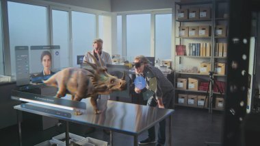 Gelişmiş arkeoloji laboratuvarı: Sanal ekran grafikleri, yapay zeka asistanı ve antik dinozorun 3D animasyonu. VR kulaklıklarındaki arkeologlar bilimsel araştırmalarını artırılmış gerçeklik kullanarak yürüttüler..