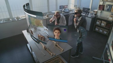 Gelişmiş arkeoloji laboratuvarı: VR kulaklıklarda çalışan iki arkeolog iskelet üzerinde çalışmalar yapıyor ve geliştirilmiş gerçeklik kullanıyor. Yapay zeka ses asistanı ve bilgi web tarayıcısıyla üç boyutlu sanal görüntü canlandırması.