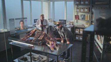 Gelişmiş arkeoloji laboratuvarı: Sanal ekran grafikleri, yapay zeka asistanı ve antik dinozorun 3D animasyonu. VR kulaklıklarındaki arkeologlar bilimsel araştırmalarını artırılmış gerçeklik kullanarak yürüttüler..