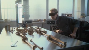 Gelişmiş arkeoloji laboratuvarı: VR kulaklık alanında arkeolog artırılmış gerçekliği kullanarak antik iskelet üzerinde çalışıyor. Yapay zeka asistanı ve Neandertal 'in 3D modeliyle holografik ekranın VFX canlandırması.