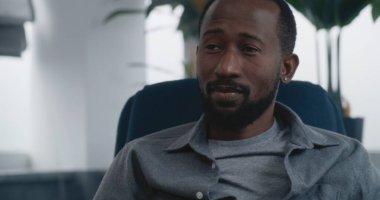 Psikoloji Ofisi: Afrikalı Amerikalı yetişkin bir adamın sandalyeye oturup terapistle konuşurken, sorunları tartışırken ve terapi ya da danışmanlık seansı sırasında çözüm ararken yakın plan çekimleri. Ruh Sağlığı.