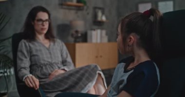 Çocuk terapistiyle danışmanlık seansında olan Asyalı okul çağındaki bir kız. Profesyonel kadın psikoloğa odaklan. Sandalyeye otur, konuş, soru sor, çocuk için terapi yap. Psikoloji.