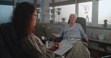 Psikoterapist ya da psikolog işyeri: Kadın uzman, aile sorunları ve zihinsel sorunlarla ilgili hastaları dikkatle dinliyor, seans sırasında notlar alıyor. Psikoloji ve akıl sağlığı.