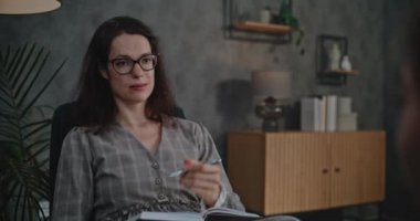 Profesyonel kadın terapist sandalyede oturur, Asyalı okul çağındaki kızla konuşur, sorular sorar, çocuk terapisi sırasında notlar alır. Çocuk psikoloğuyla danışmanlık seansına giden bir çocuk. Ruh Sağlığı.