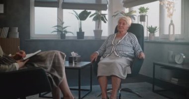 Üzgün yaşlı kadın sandalyede oturup kadın psikoterapist ya da psikologla psikolojik sorunları tartışıyor. Yaşlı hasta terapi seansı sırasında zihinsel sorunlardan bahsediyor. Psikoloji kavramı.