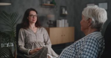Terapi seansında kadın psikolog veya psikoterapist sandalyeye oturur ve yaşlı kadınları dinler. Terapist hastayla iletişim kurar, notlar alır. Psikoloji ve akıl sağlığı kavramı.
