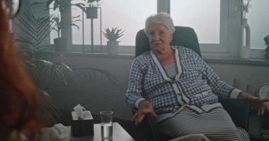 Psikolog ya da psikologla randevusu olan yaşlı bir kadın. Yaşlı müvekkil koltukta oturuyor, ahlaki durumu hakkında konuşuyor, danışmanlık seansında olumlu duygular paylaşıyor. Psikoterapi kavramı