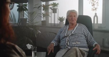 Terapi seansındaki yaşlı kadın yaşlanmayla ilgili duygularını ve duygularını paylaşıyor. Kadın hasta zihinsel sorunlardan bahsediyor, yaşadığı depresyondan bahsediyor. Yaşlılar için psikolojik yardım. Ruh Sağlığı.