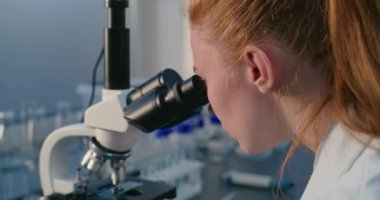 Kadın mikrobiyolog mikroskop altında test örneklerini analiz ediyor, ilaç geliştiriyor. Parlak bilim adamı, kimyager yüksek teknolojili ekipman kullanıyor. Bilimsel araştırma.