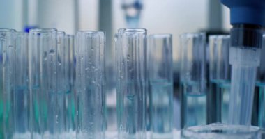 Tıp laboratuvarı: Kimyager ya da bilim adamı pipetle araştırma yapmak için mavi sıvıyı test tüplerine döküyor. Aşı geliştirme. Gelişmiş farmakoloji laboratuvarı. Bilimsel yöntem. Makro Yakın Çekim.