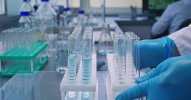 Tıbbi bilim laboratuvarı: Kimyager ya da bilim adamının cam şişedeki pipetle mavi sıvıyı alıp analiz için test tüplerine boşaltması. Gelişmiş farmakoloji laboratuvarı. Bilimsel yöntem.