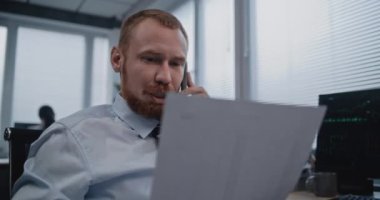 Modern ofiste: Profesyonel finans uzmanı cep telefonuyla iş müşterisiyle konuşur, kağıt belgelerini analiz eder. Başarılı borsacı borsa şirketinde çalışıyor. Finansal hizmetler.
