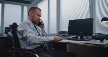 Analizci, satış departmanının sonuçlarını cep telefonuyla raporlayarak ve tartışarak kağıtları inceliyor. Bilgisayar ekranında gösterilen finansal göstergeler ve diyagramlar. İş dünyası.