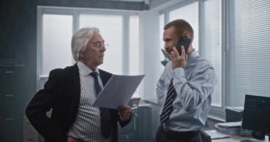 Genç borsacı nöbetçi müşterilerle hisse alma konusunda konuşuyor. Finansal danışman, broker danışmanı yatırımcı, telefonla iletişim kuruyor. Büyük patron görüşmeleri kontrol ediyor..