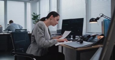 Büyük finans şirketinin yöneticilerinin işyeri: Yetişkin, güzel kadın analist, döviz kurlarında değişiklik var mı diye kağıt belgelerdeki verileri kontrol ediyor. Hisse senedi ve sermaye piyasaları kavramının izlenmesi.