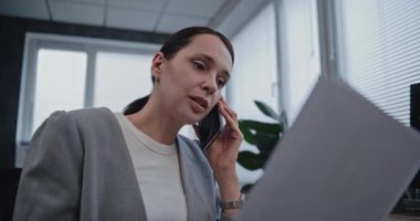 Uluslararası borsa şirketinde çalışan güzel bir genç kadının portresi. Kadın borsacı cep telefonuyla hisse senedi almak için müşteriyle konuşuyor. Ticaret ve iş konsepti.