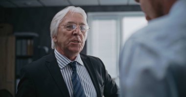 Modern ofiste kızgın patron sinirine hakim olamıyor, erkek şirket çalışanına bağırıyor. Kıdemli takım lideri ve finans uzmanı başarısız iş anlaşması yüzünden kavga ediyorlar. Uluslararası şirket veya banka.