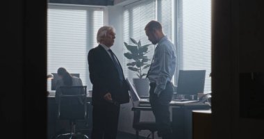 Uluslararası bankanın modern ofisinde, saldırgan patronun gazeteleri kontrolden çıkıyor ve adama bağırıyor. Kıdemli takım lideri, başarısız iş anlaşması yüzünden erkek şirket çalışanıyla tartışıyor. Yavaş Hareket.