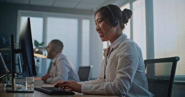 Çağrı merkezi: Asyalı dost canlısı kadın yardım hattı operatörünün kulaklıkla konuşması, bilgisayar kullanması, online müşteri yardımı sağlaması. Teknik destek uzmanlarından oluşan çok ırklı bir ekip.