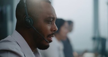 Afrika kökenli Amerikalı teknik destek uzmanının portresi. Kulaklık uzmanı. Müşteriyle sohbet ediyor. Müşteri temsilcisi çağrı merkezinde çalışıyor..