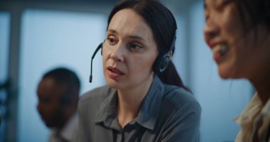 Çevrimiçi müşteri destek servisi: İki kadın teknik destek uzmanının kulaklıklarda müşteriyle sohbet etmesi. Modern çağrı merkezinde çalışan profesyonel yardım hattı operatörleri.