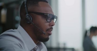 Afrika kökenli Amerikalı yardım hattının operatörünü kapatın. Müşteriyle telefonda sohbet edin. Müşteriye çevrimiçi yardım sağlayın. Teknik destek uzmanı çağrı merkezinde çalışıyor..