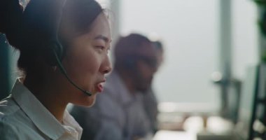 Asya E-Ticaret Müdürü 'nün kulaklıkla müşteriyle telefonda konuşurken çevrimiçi yardım sağlamasını kapatın. Teknik destek uzmanları çağrı merkezinde çalışıyor..