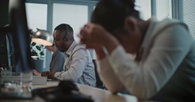 Merkezi ara: yorgun Asyalı kadın yardım masası uzmanının başını tutup stres yapmasını engelle. Afrikalı Amerikalı çalışanlar meslektaşlarını destekliyor. Akıl sağlığı yardım hattı. Çevrimiçi müşteri servisi.